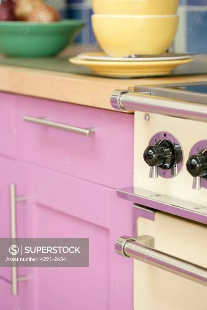 Close-up of oven beside modern pink kitchen cupboard