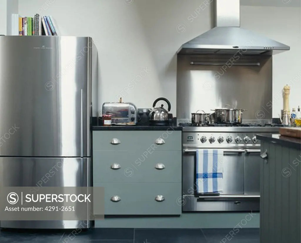 Stainless steel large fridge freezer and range oven in modern kitchen with toaster and kettle on grey fitted cupboard