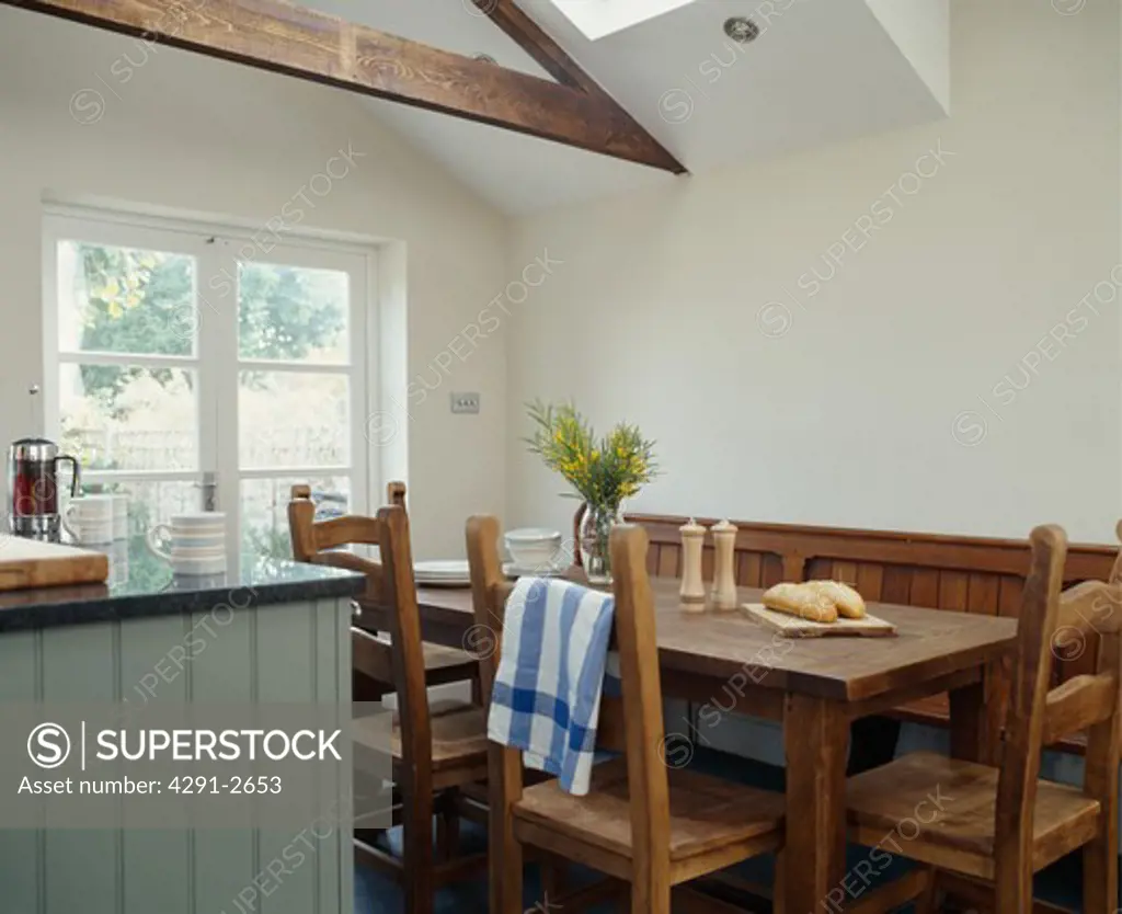 Wooden table and chairs in white dining room extension with apex ceiling