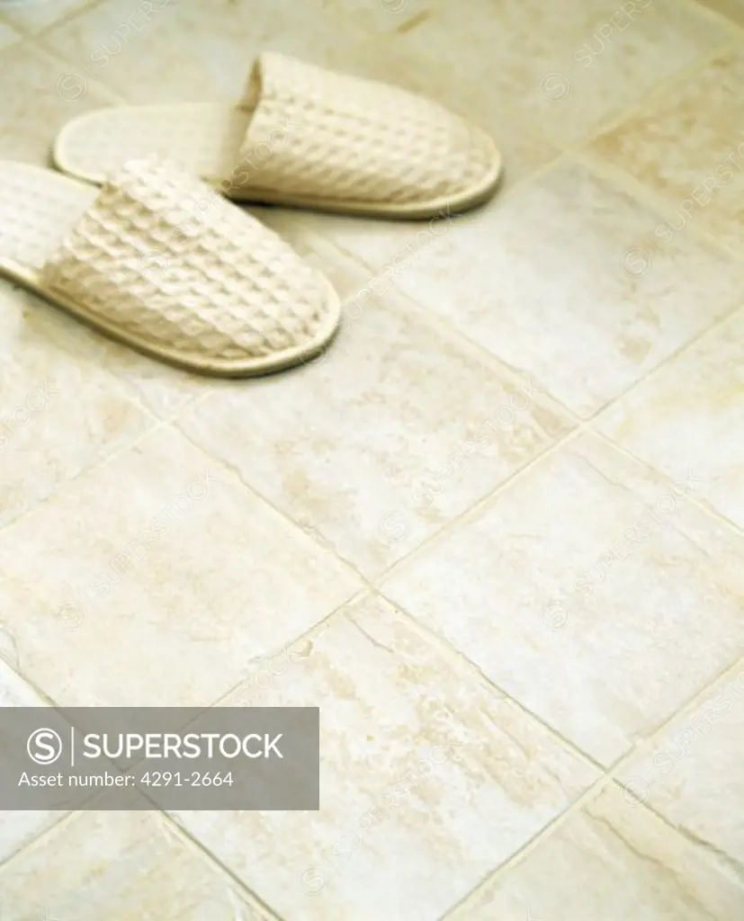 Close-up of beige slippers on beige tiled floor