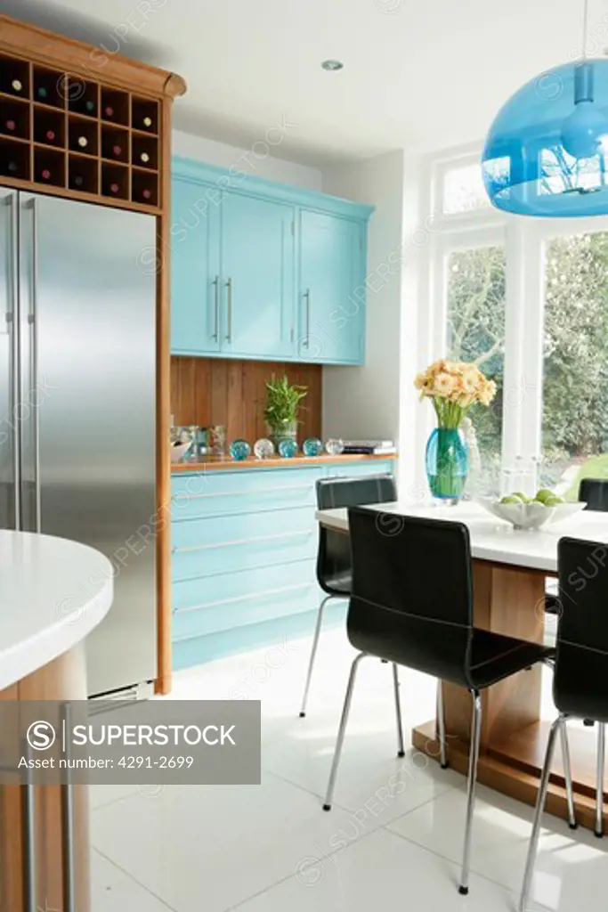 American-style stainless steel fridge freezer in modern white kitchen with white flooring and pale turquoise cupboards