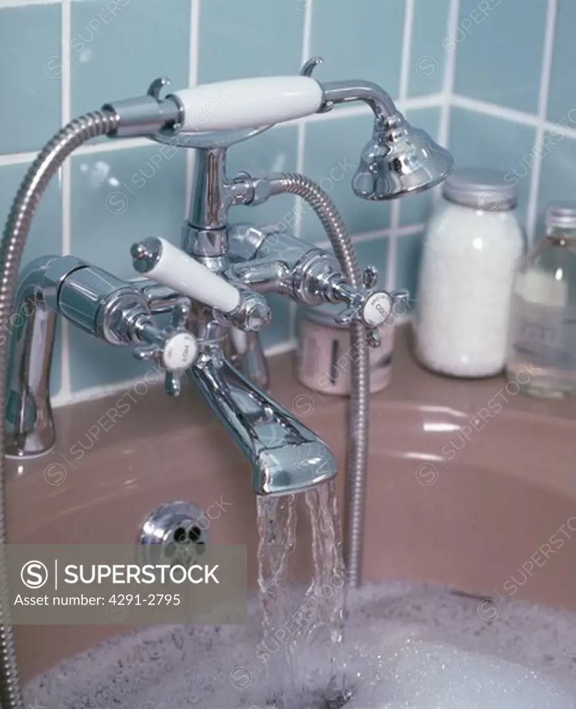 Close-up of shower head with taps pouring water into bath