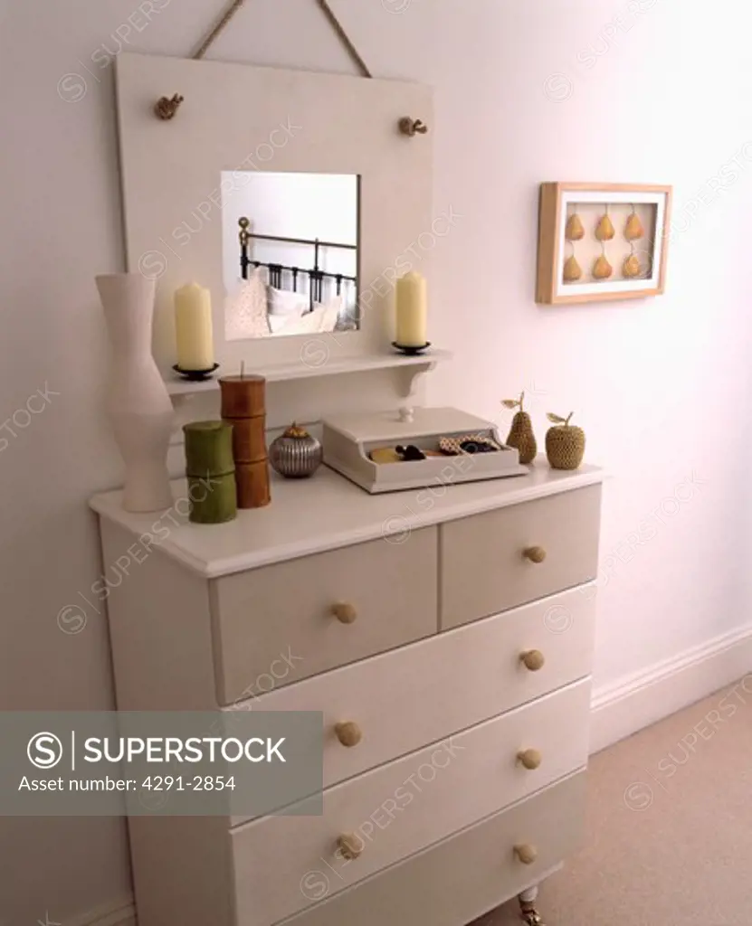 Painted mirror and chest of drawers in a modern white bedroom