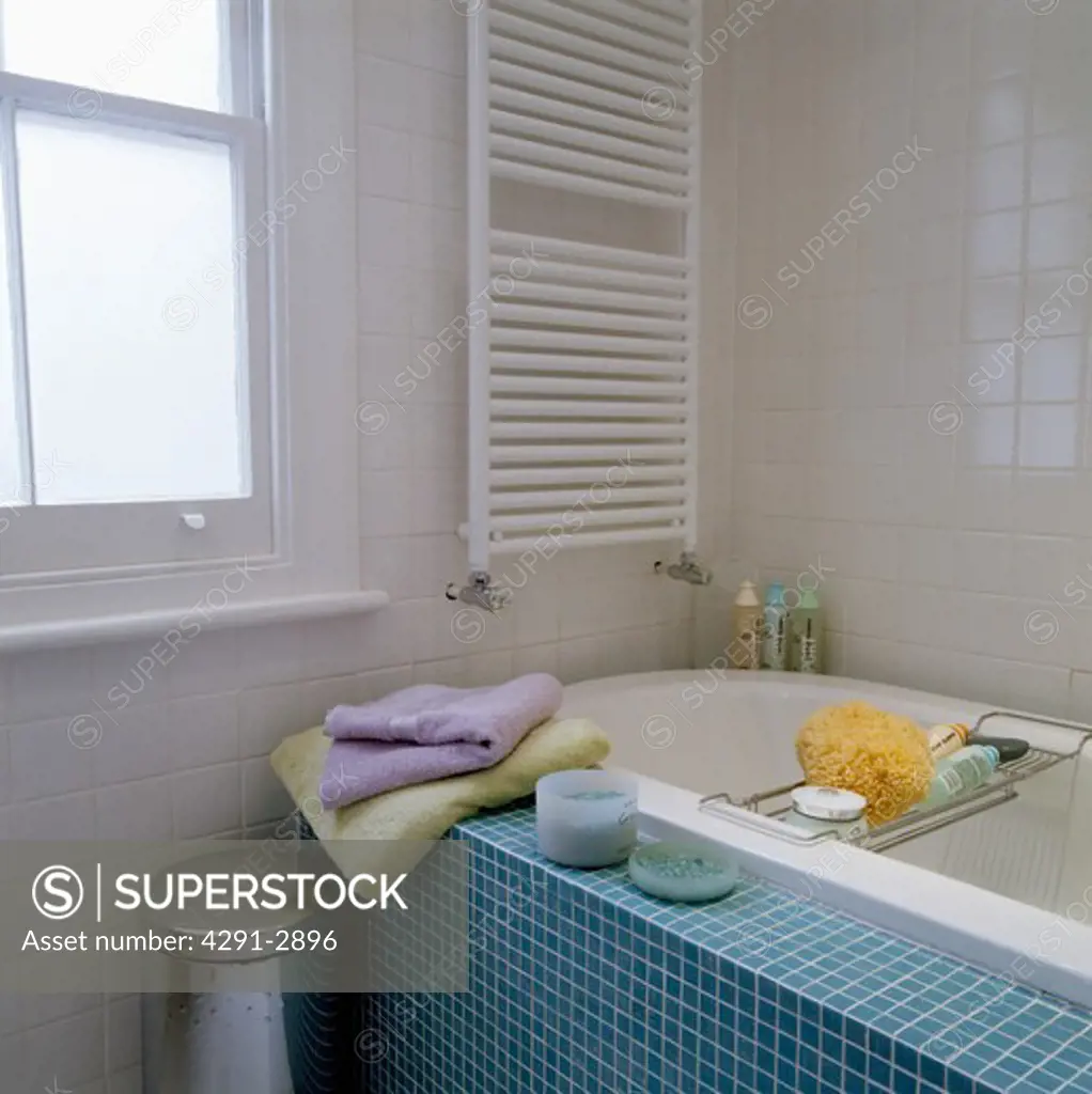 Small white bathroom with turquoise tiled bath side