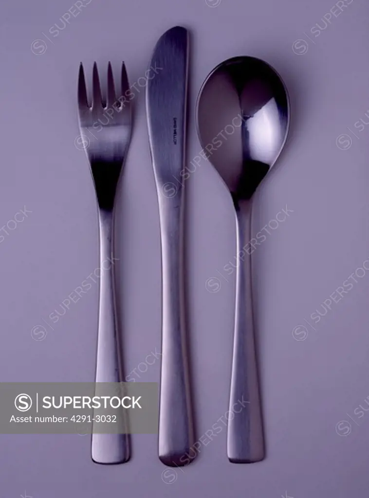 Close-up of modern stainless-steel knife and fork with spoon