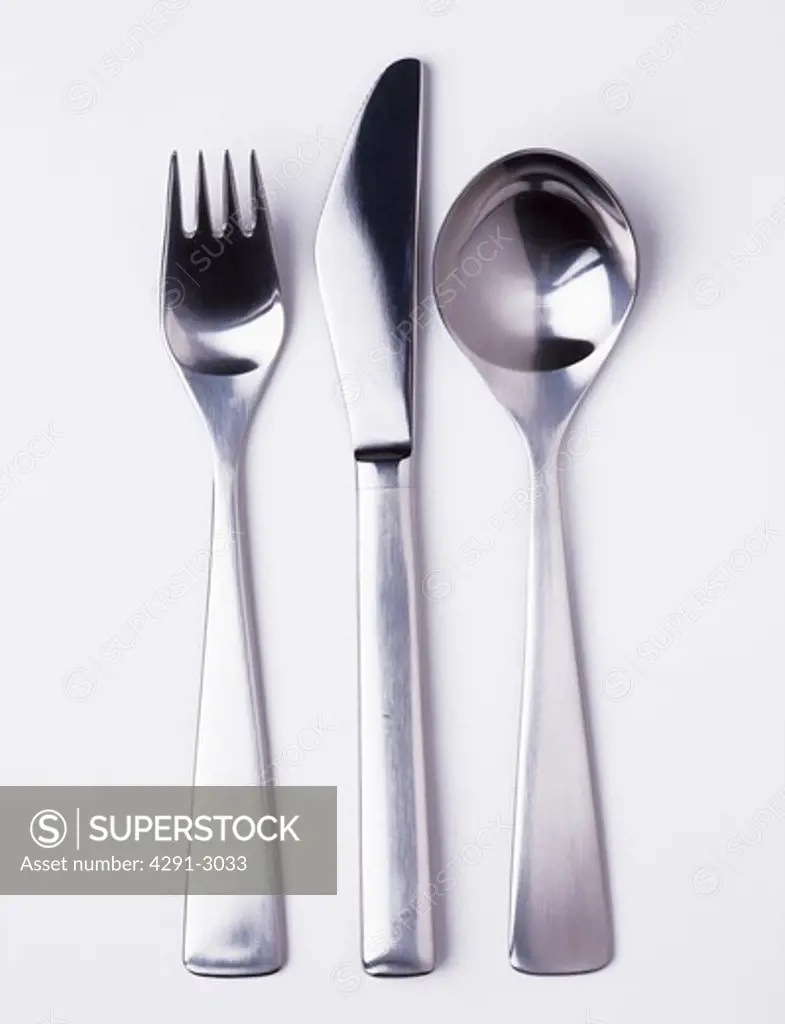 Close-up of modern stainless-steel knife and fork with spoon