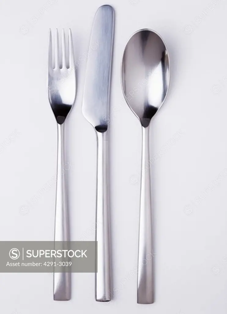 Close-up of stainless-steel knife and fork with spoon