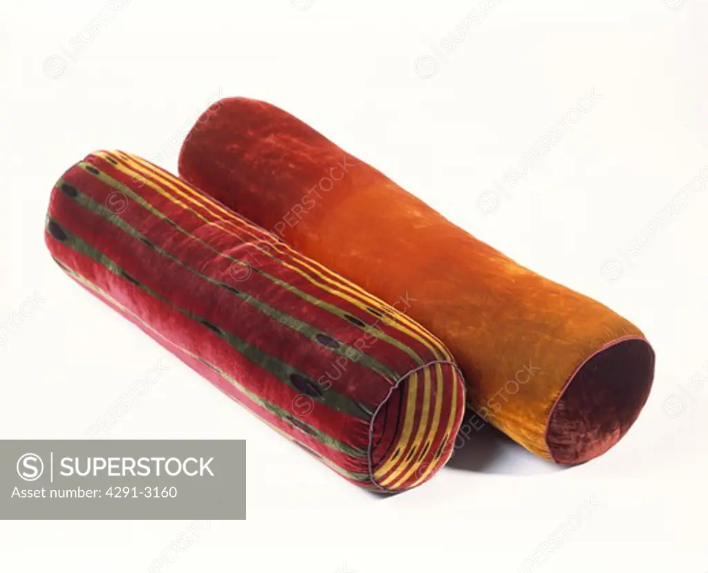 Close-up of two dark red velvet bolster cushions