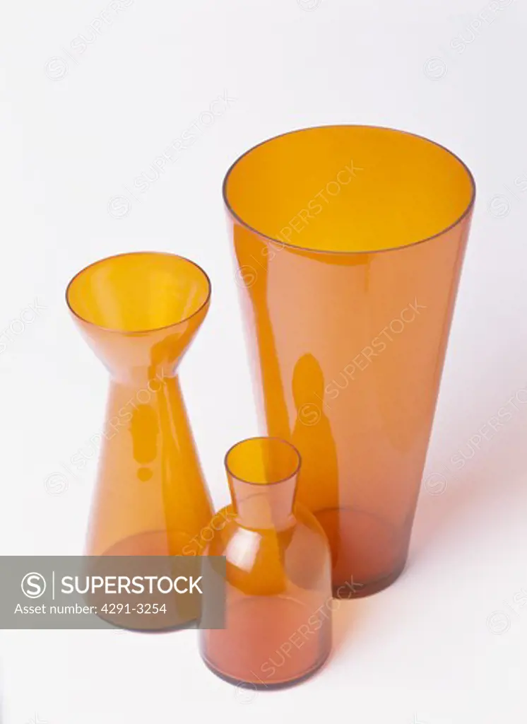 Close-up of three shaped orange vases