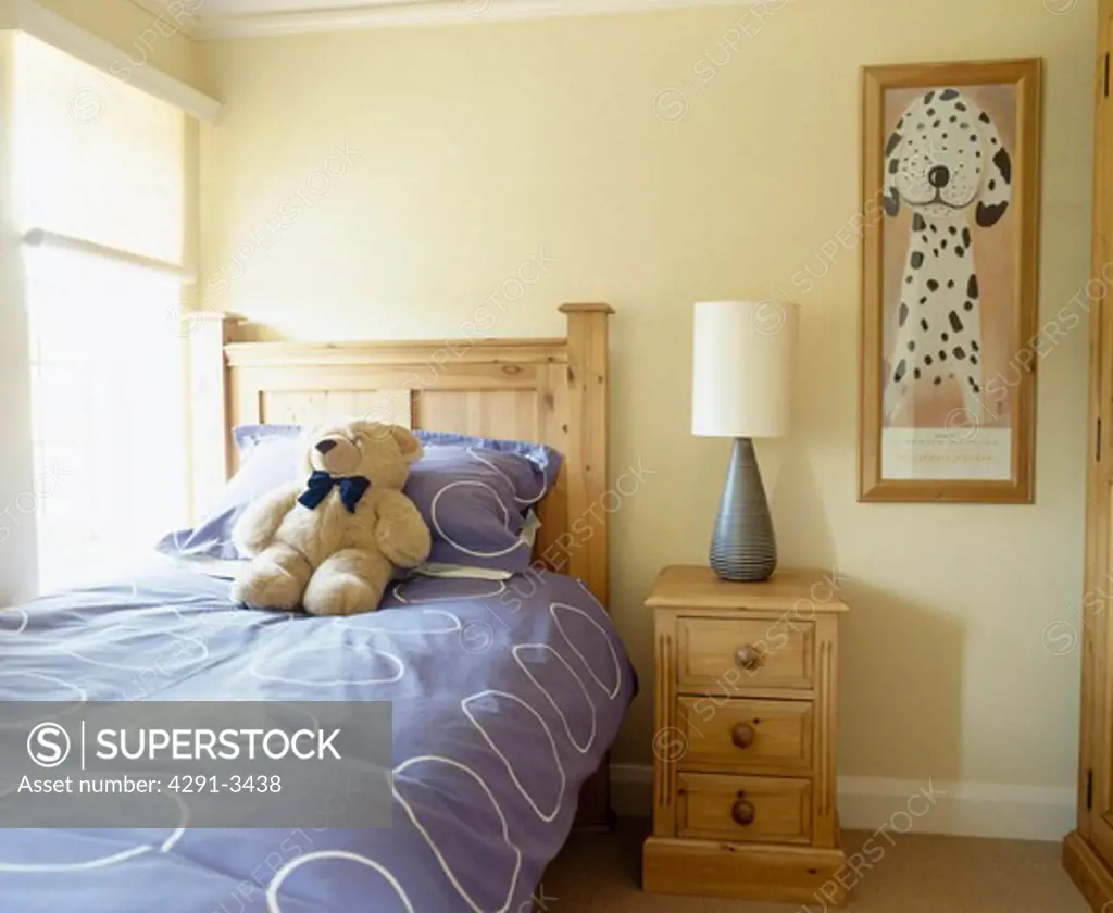 Teddybear on pine bed with blue duvet in child's bedroom