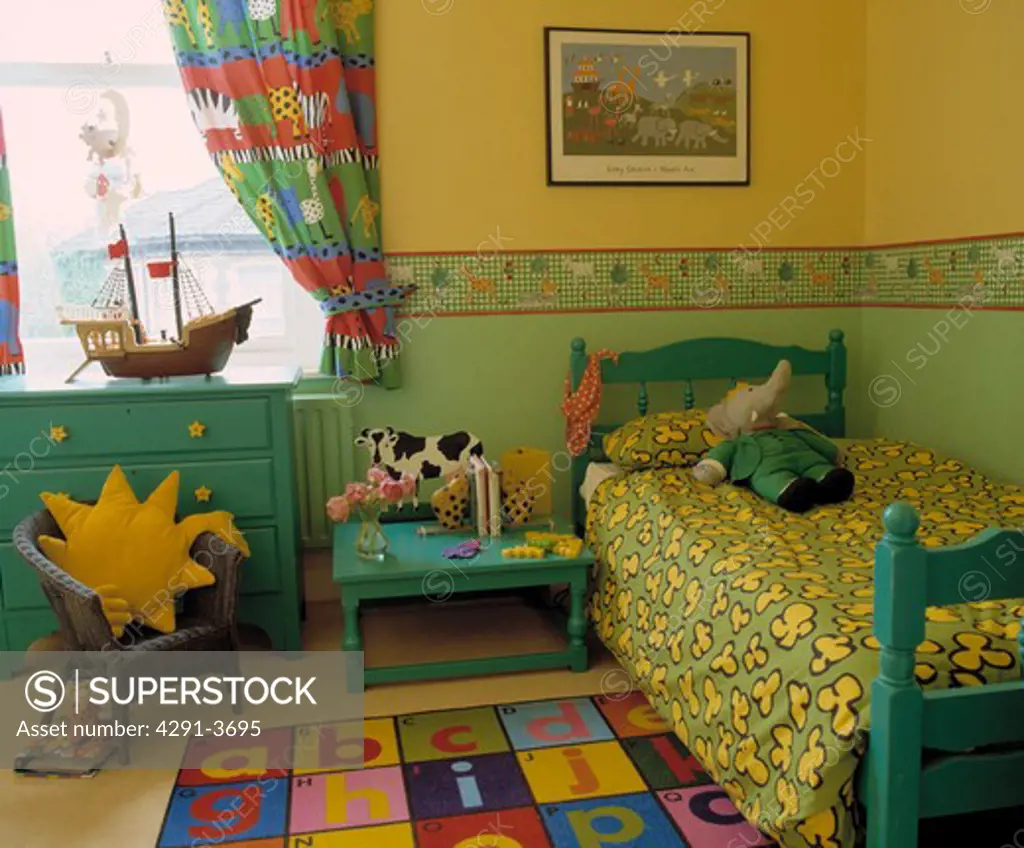 Green and yellow duvet on green wooden bed with yellow and green wallpaper and dado border