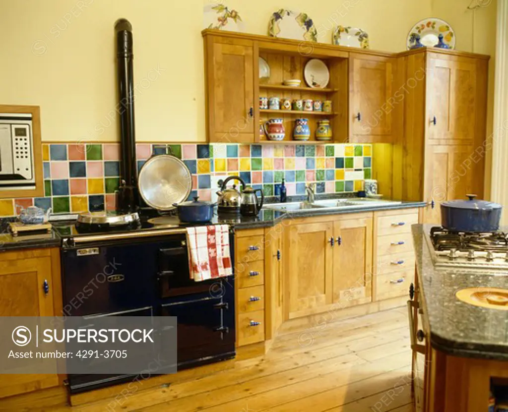 Black Aga oven in traditional yellow kitchen with wooden fitted units