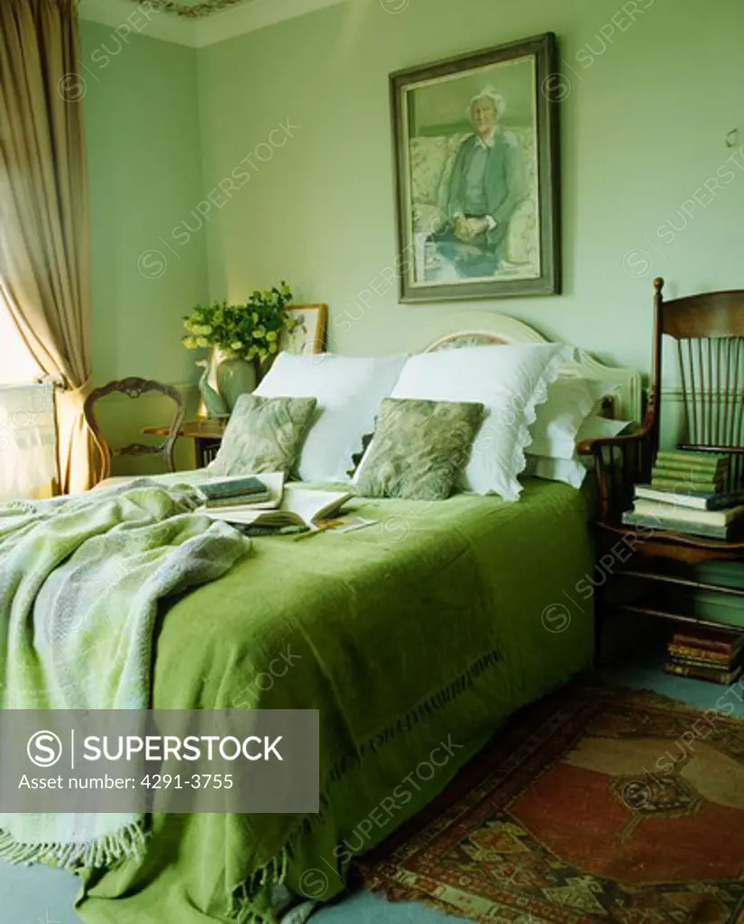 White pillows and bright green bedcover with toning checked throw on bed in pastel green bedroom