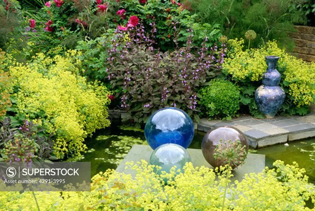 Glass globes and small pond in country garden