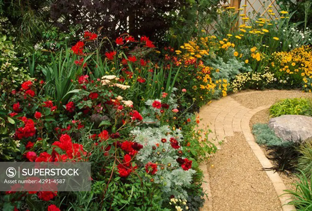 Gravel path and colourful herbaceous border in country garden in summer