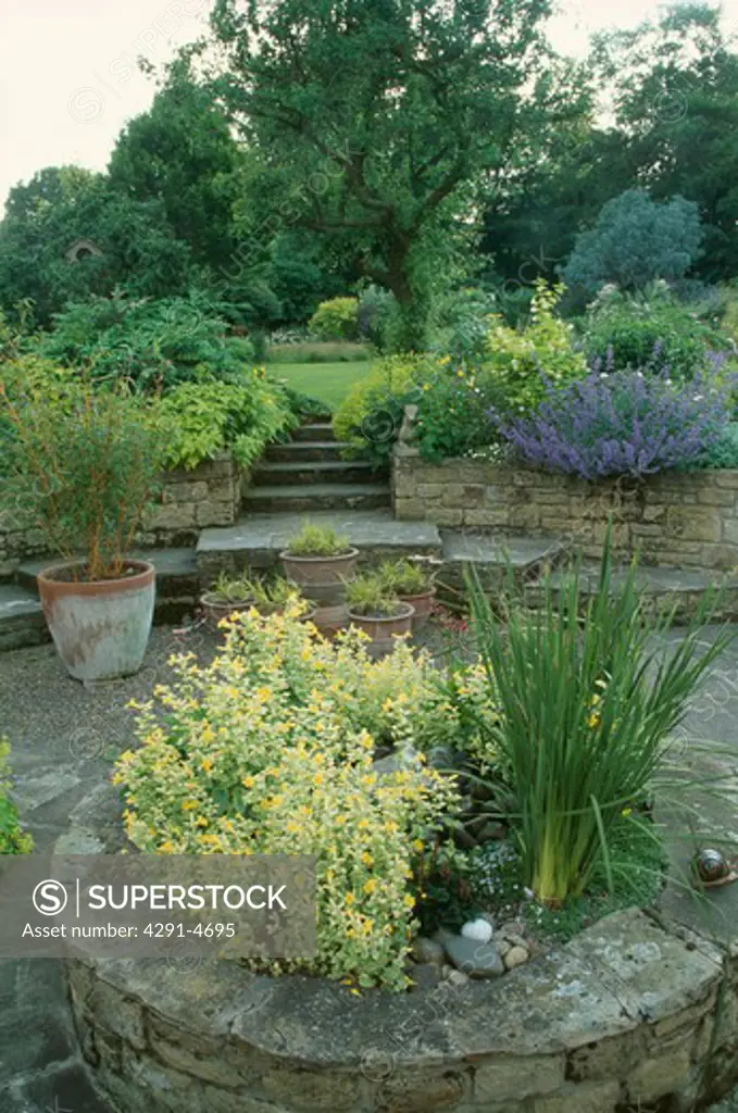 Raised circular bed with stone edging in large country garden