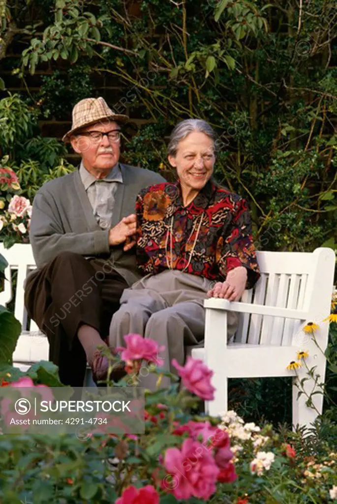 Portrait of Beth Chatto and Christopher Lloyd sitting on white garden bench