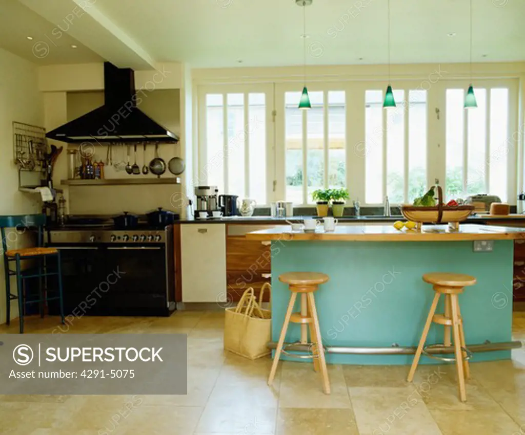 limestone flooring in large modern kitchen with turquoise island unit