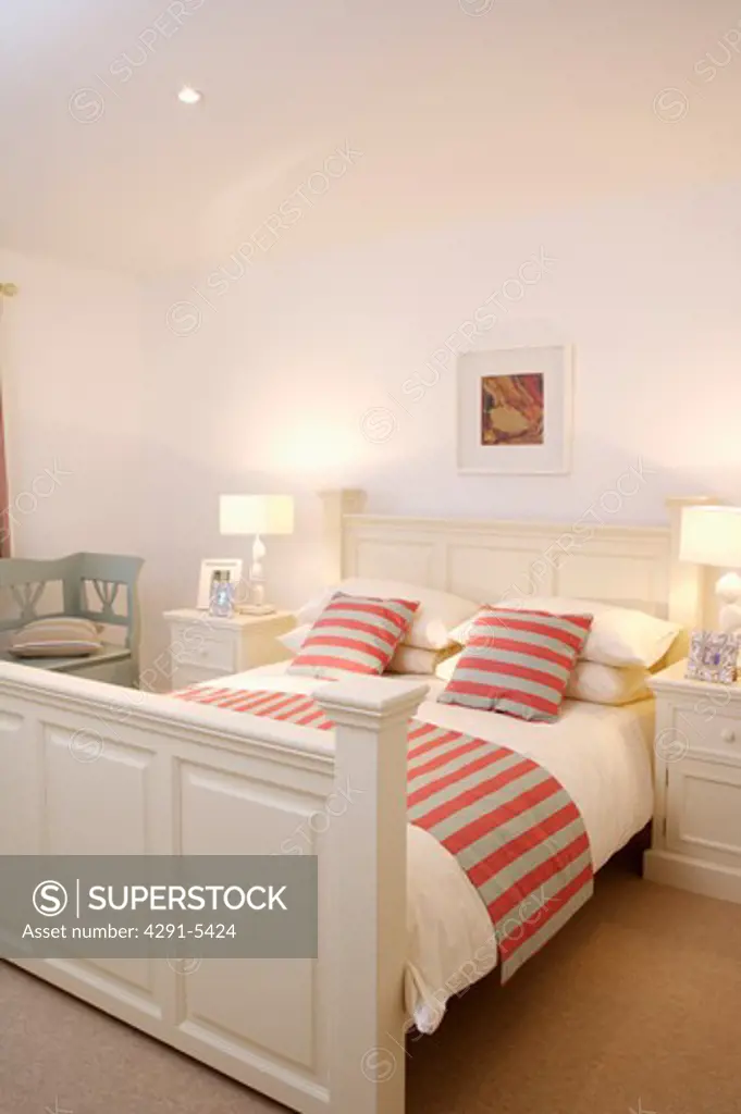 Red and grey cushions striped cushions and throw on white wooden bed in modern white bedroom