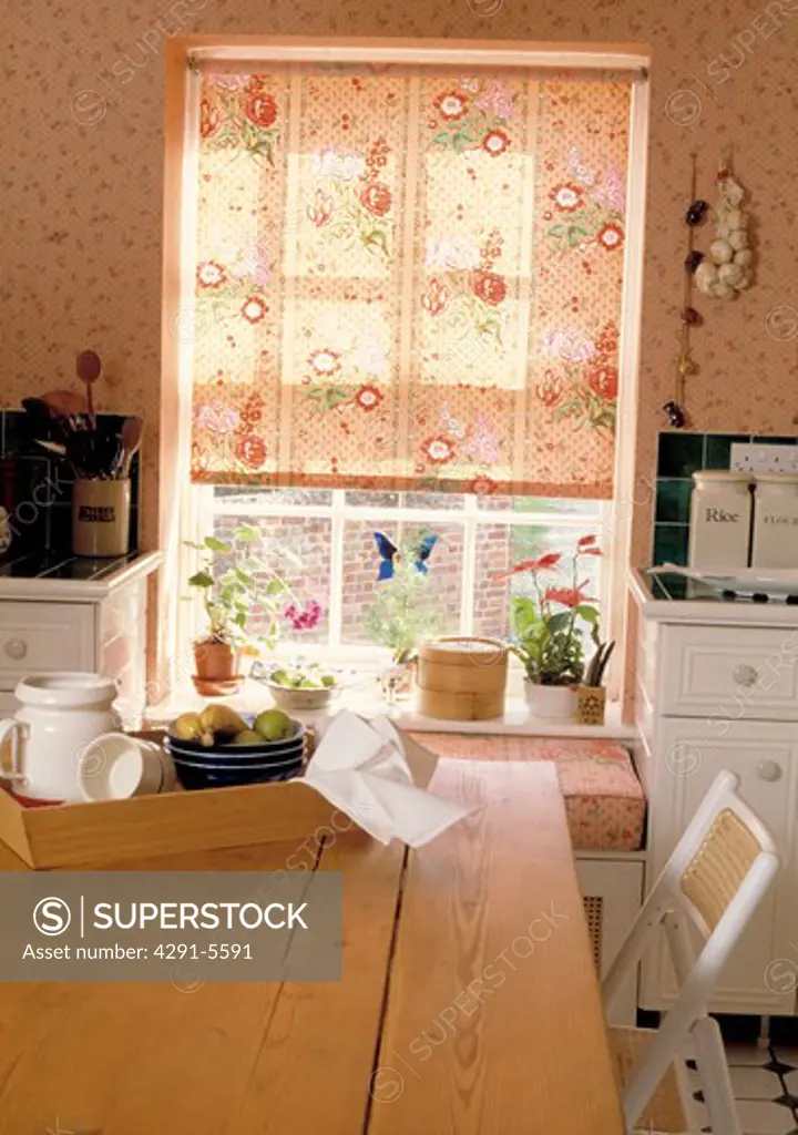 Peach floral blind on window in kitchen with wooden tray on pine table