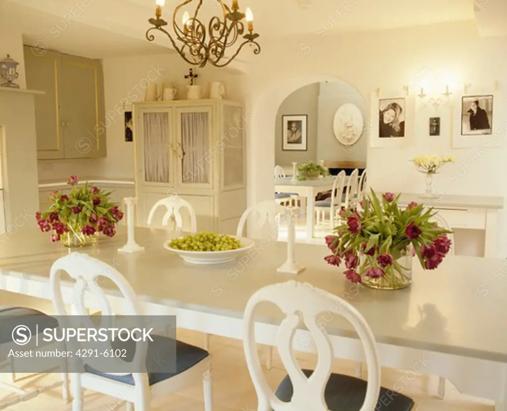 Red tulips on white table with white chairs in white dining room