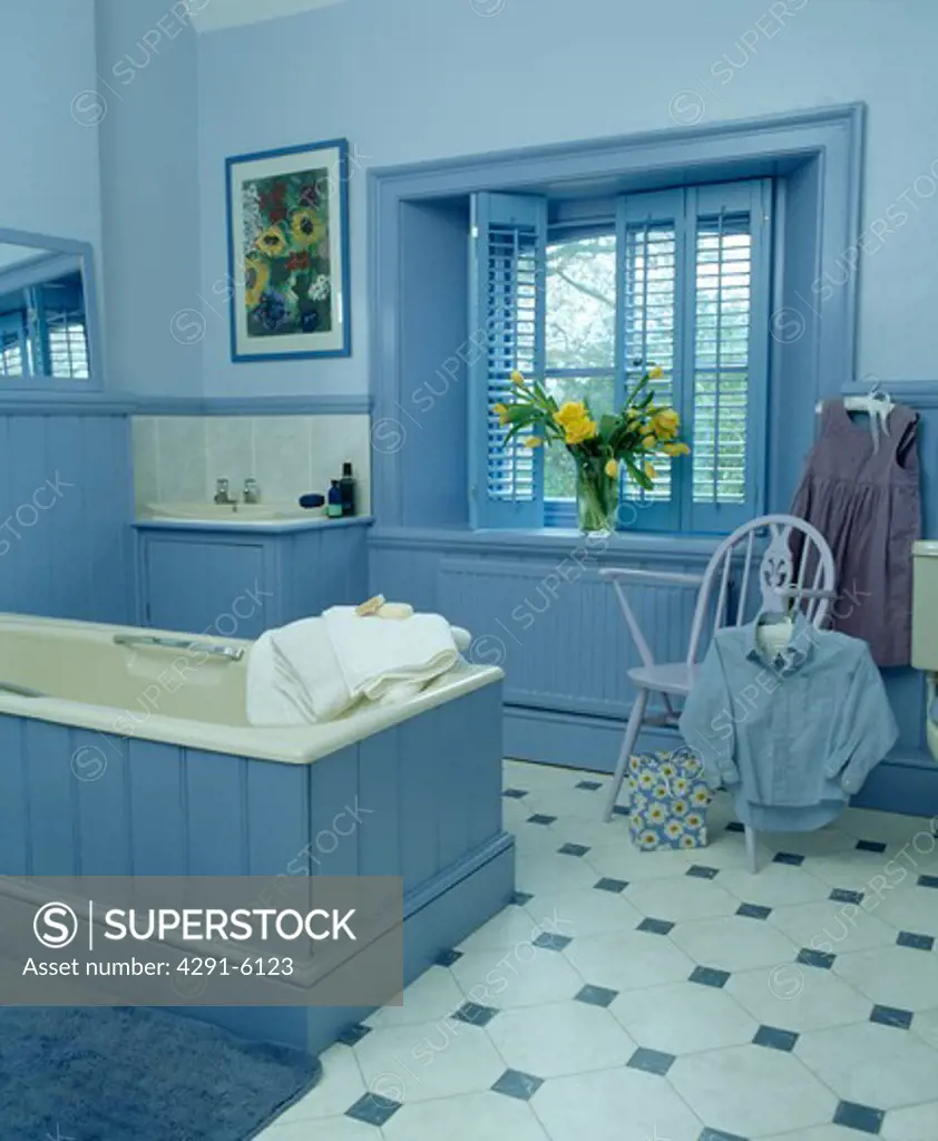 Blue plantation shutters in blue bathroom with tonque and groove panelled bath