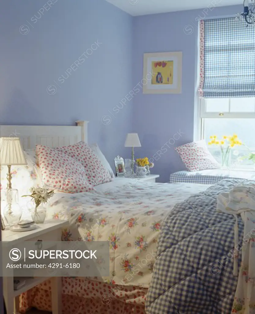 Floral bedlinen on bed in blue country bedroom