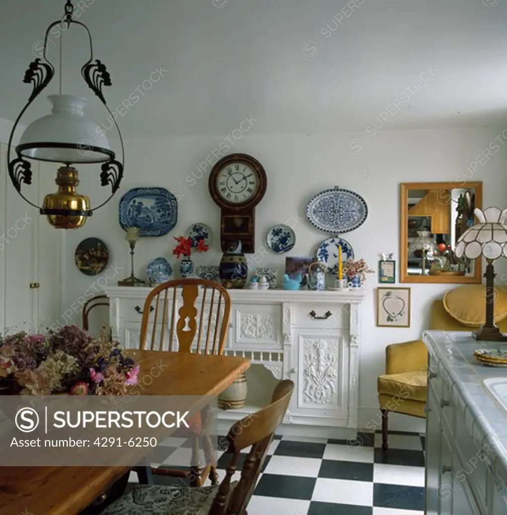 Victorian style lantern above wooden table and chairs in country kitchen with black and white flooring