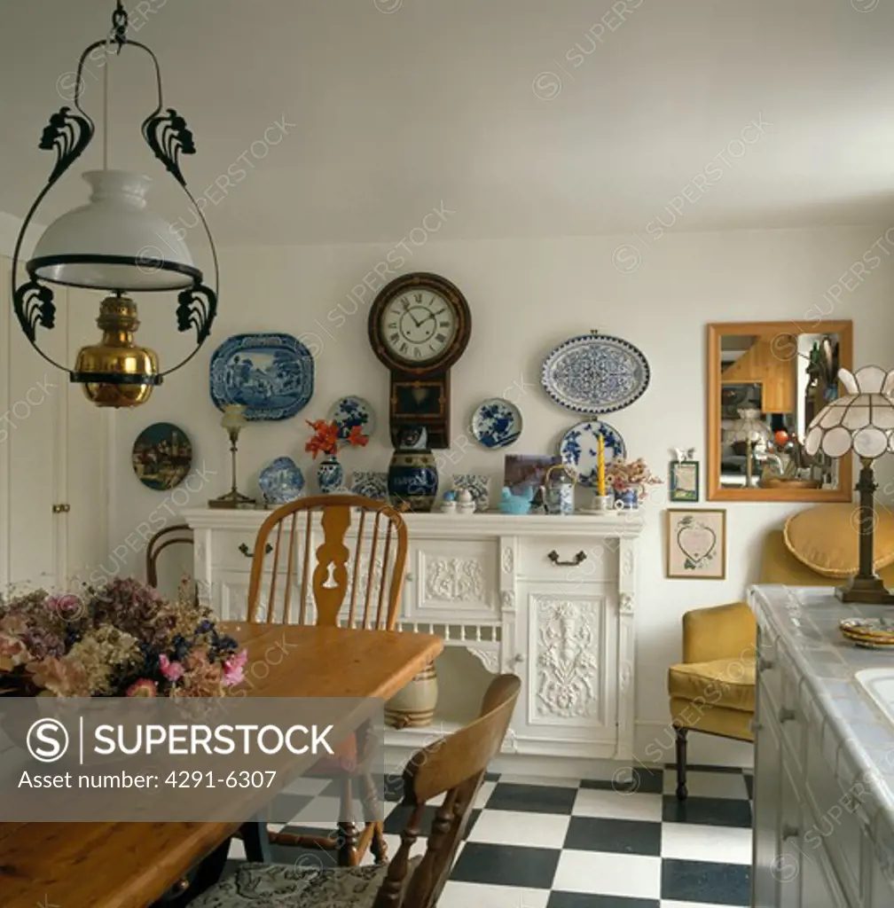 Victorian style lamp over wooden table in white country dining room with clock on wall above white sideboard