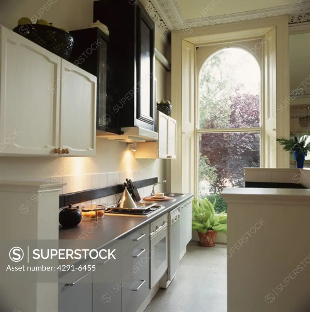Stainless steel worktops in grey galley kitchen with tall sash window