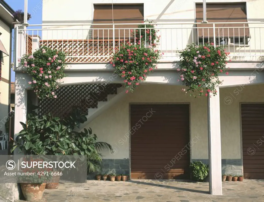 Red and pink geraniums on balcony above courtyard of Turkish house