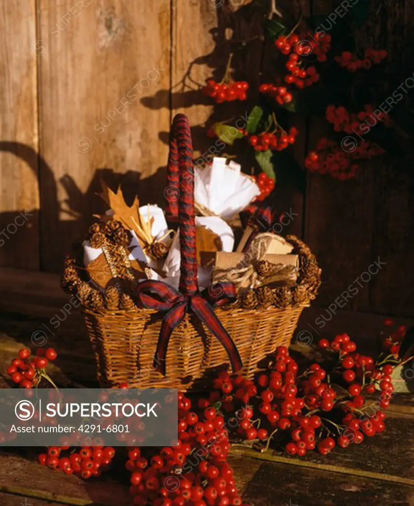 Close-up of red berries and basket of gift-wrapped presents