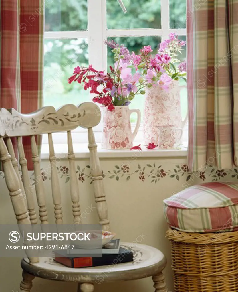 Painted white chair in front of window with stencilling below windowsill