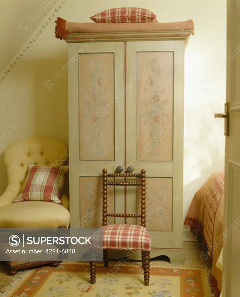 Small chair in front of hand-painted and stencilled wardrobe