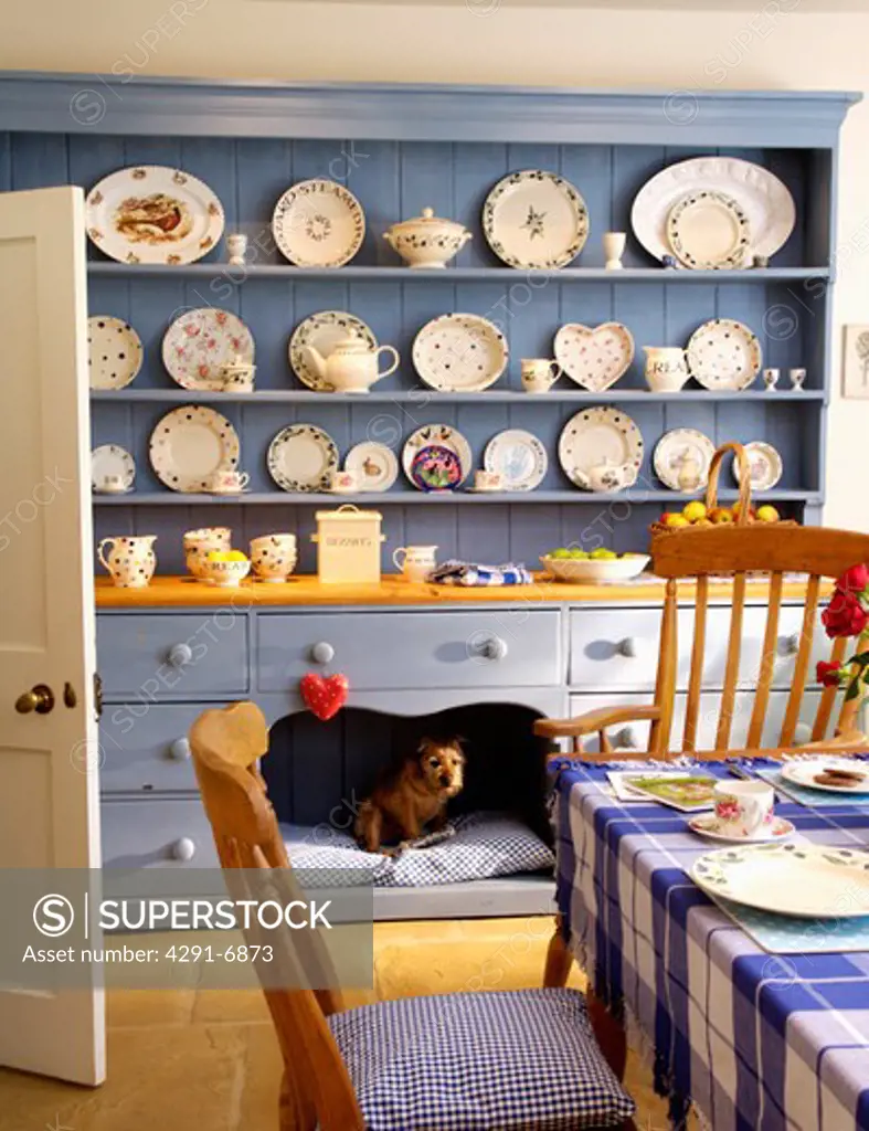 Collection of crockery on large blue painted dresser in traditional country kitchen