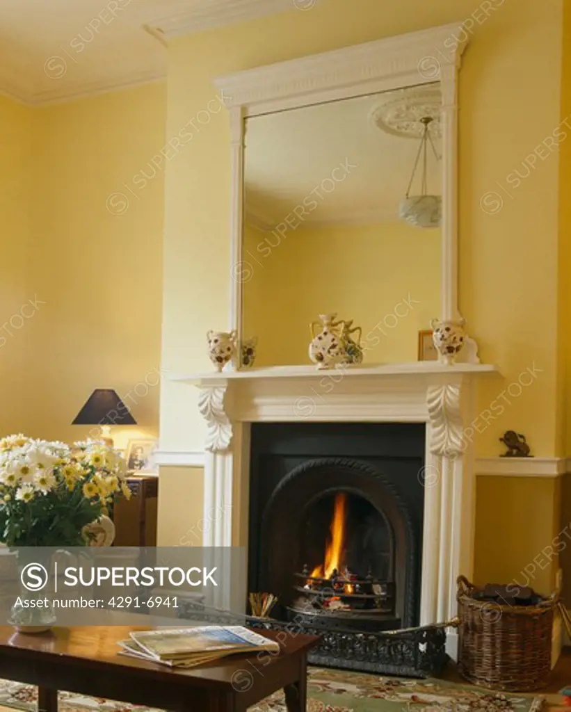 White mirror above white fireplace in pastel yellow livingroom