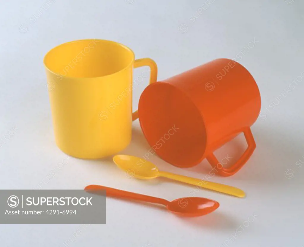 Close-up of red and yellow plastic mugs with matching spoons