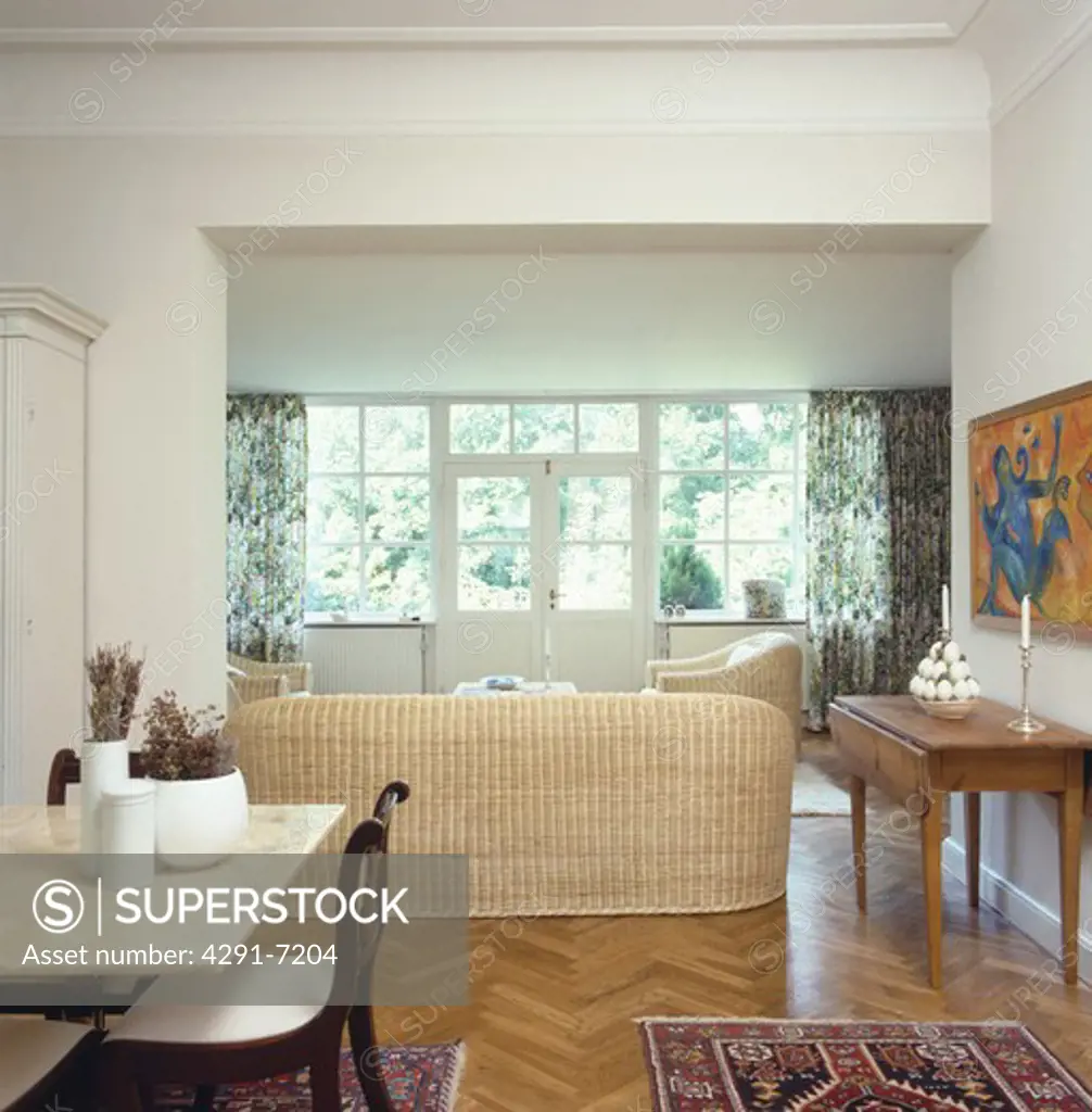 Marble topped table and wicker sofa in modern living and dining room with wooden parquet floor