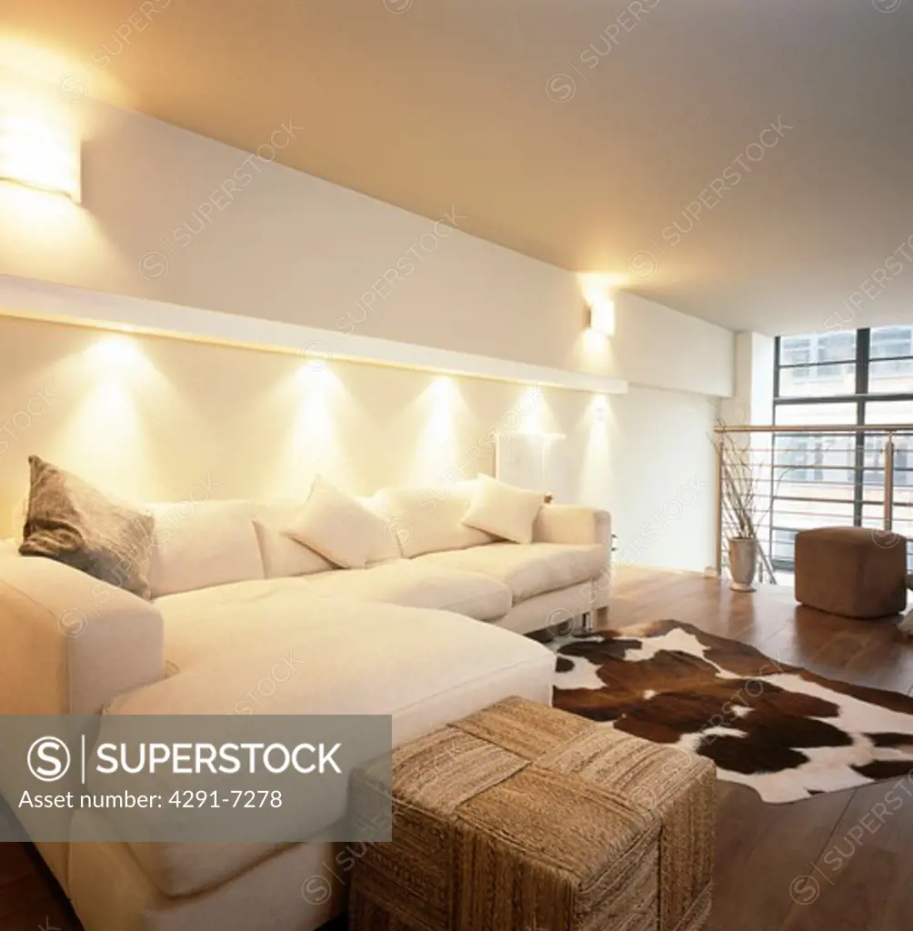 Downlighting above cream corner sofa in modern white loft conversion living room