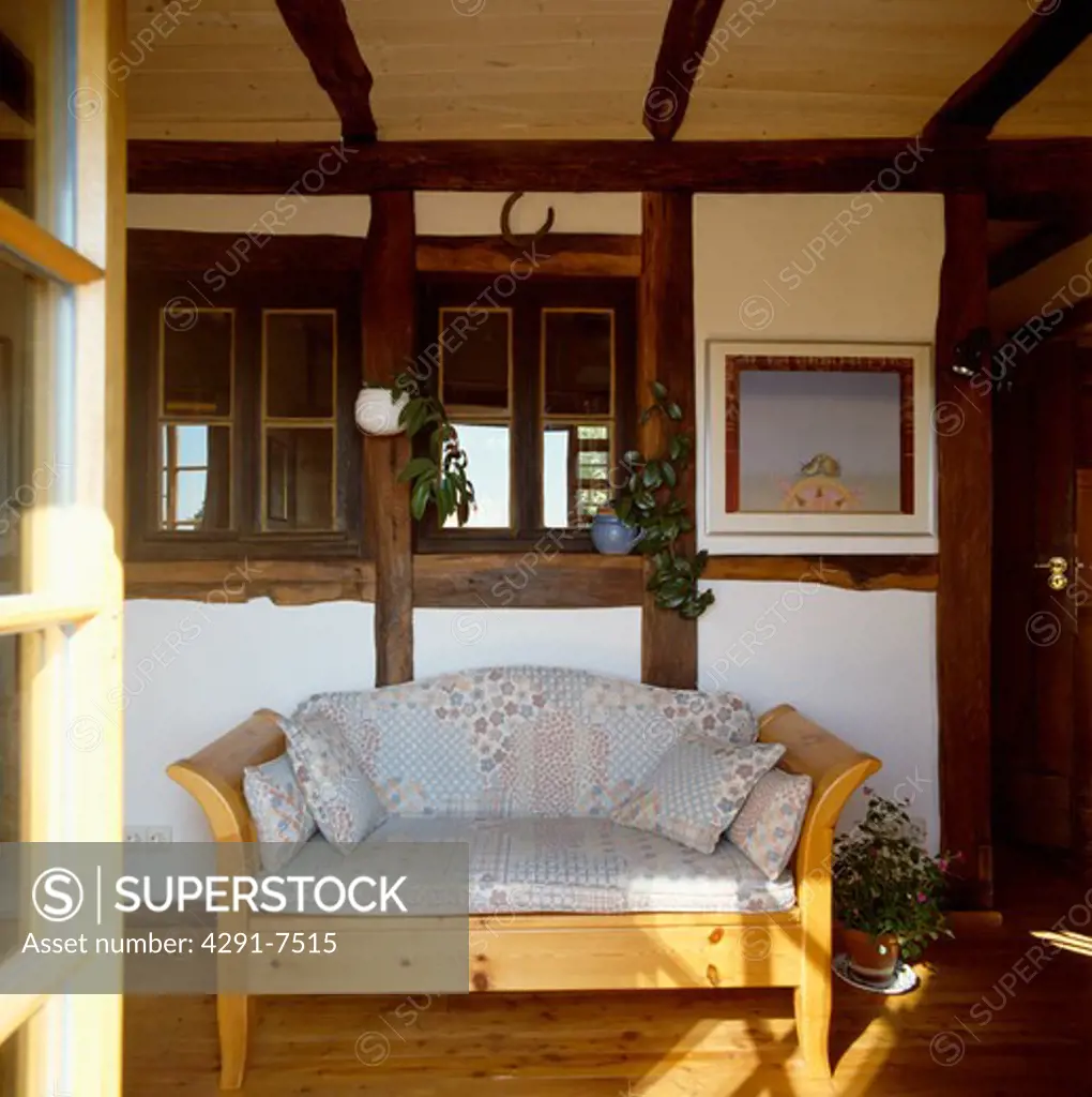 Cushions on small pine settle below internal window in timbered hall