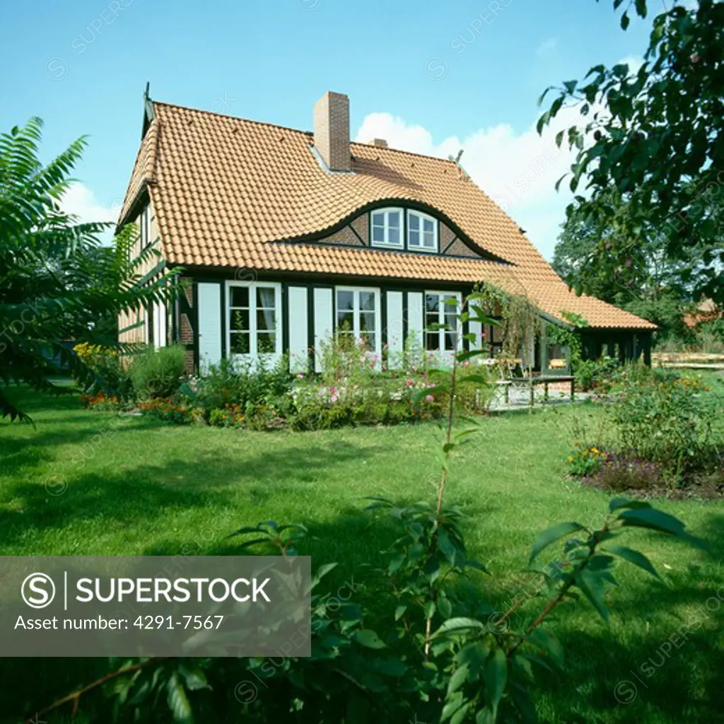 Lawn in front of single-storey country cottage with dormer window