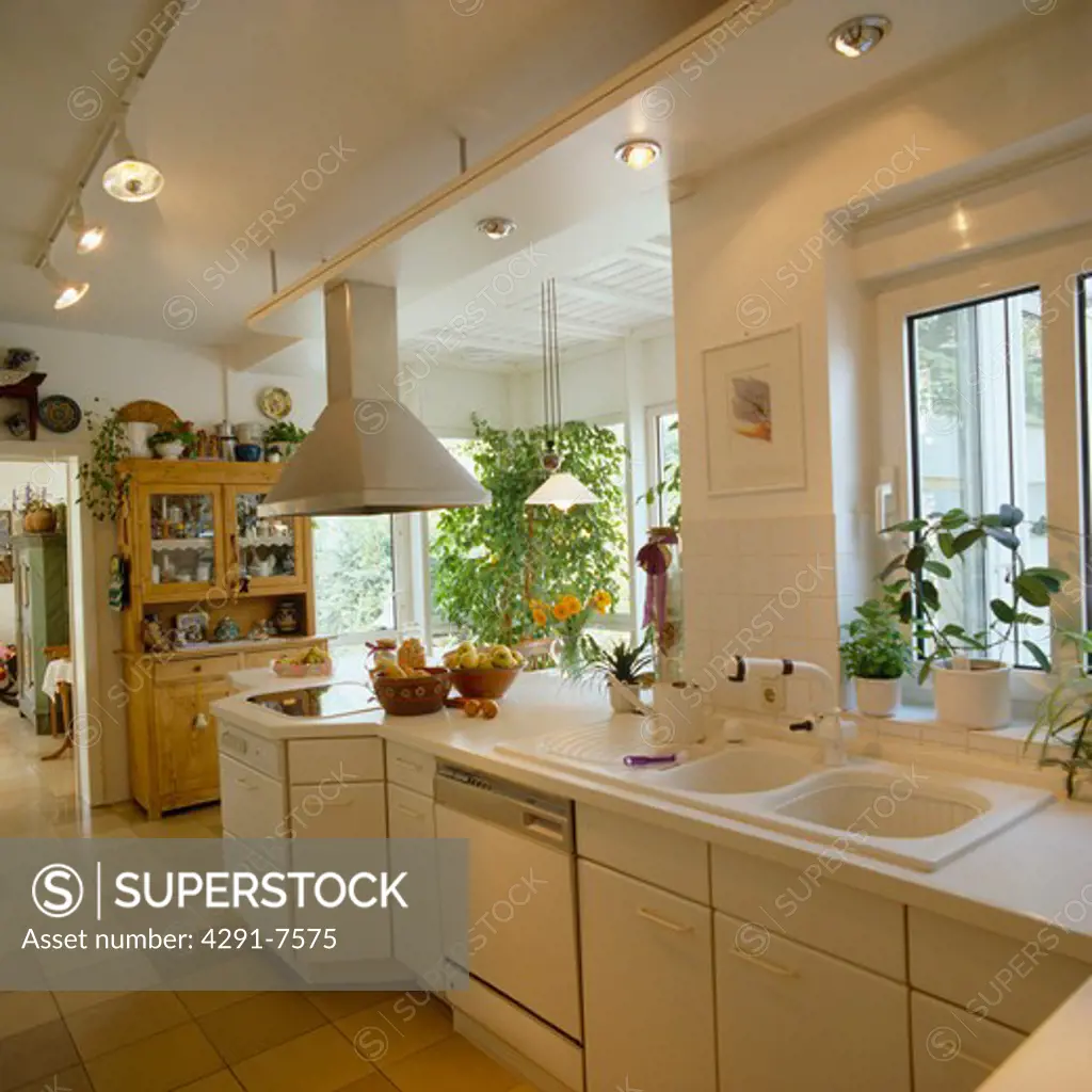 Spotlights on ceiling tracks in modern white kitchen with double white sinks