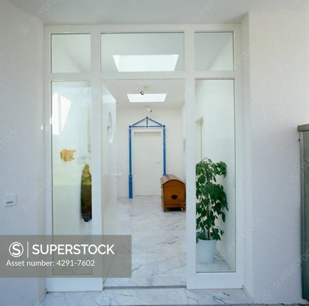 Glass doors to modern white hall with marble flooring