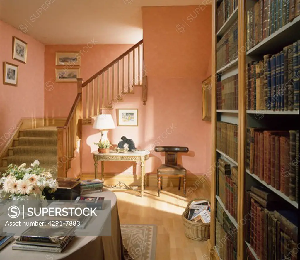 Wall of bookshelves and books on linen table cloth in terracotta hall