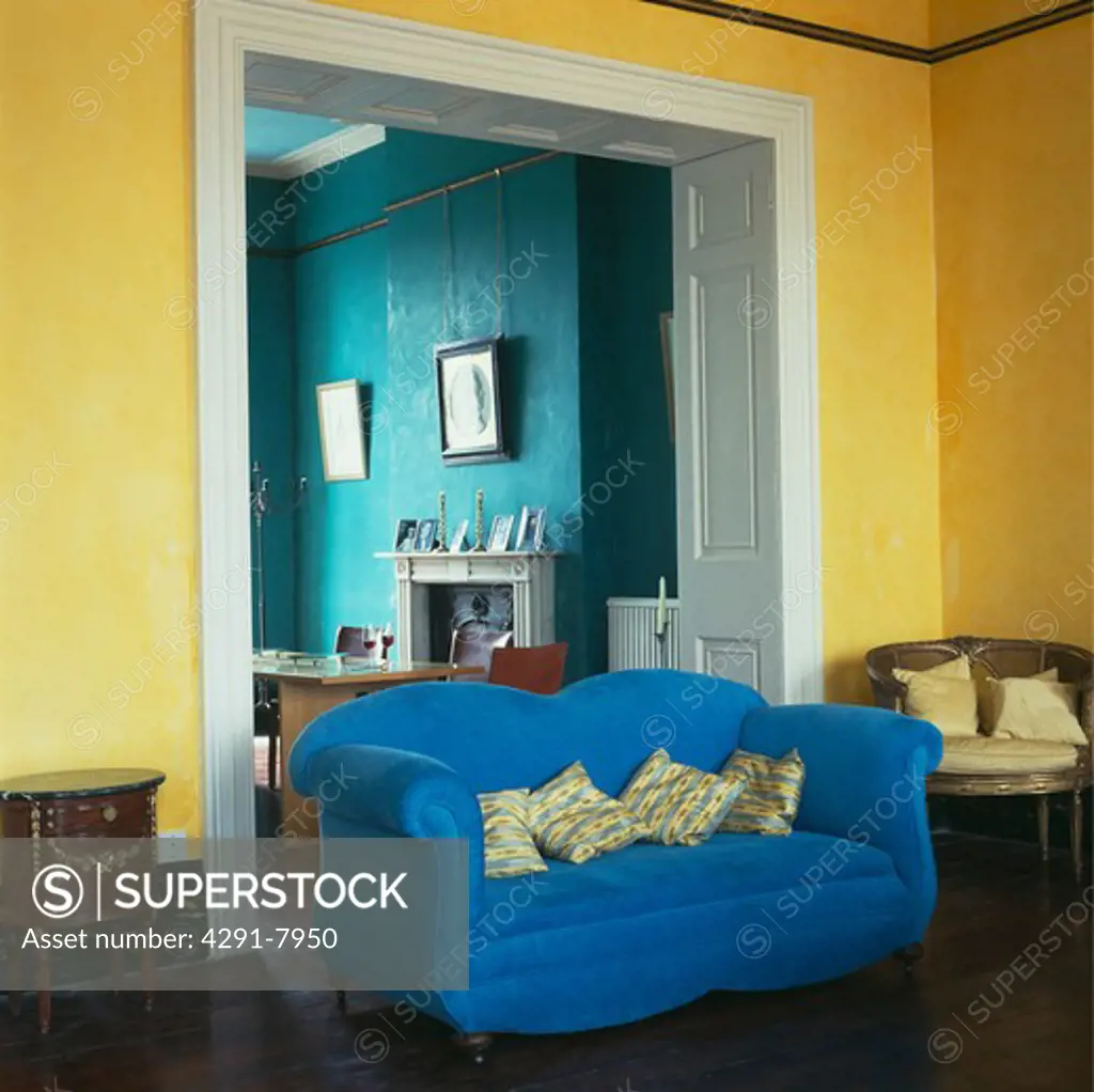 Bright blue sofa in doorway of yellow living room