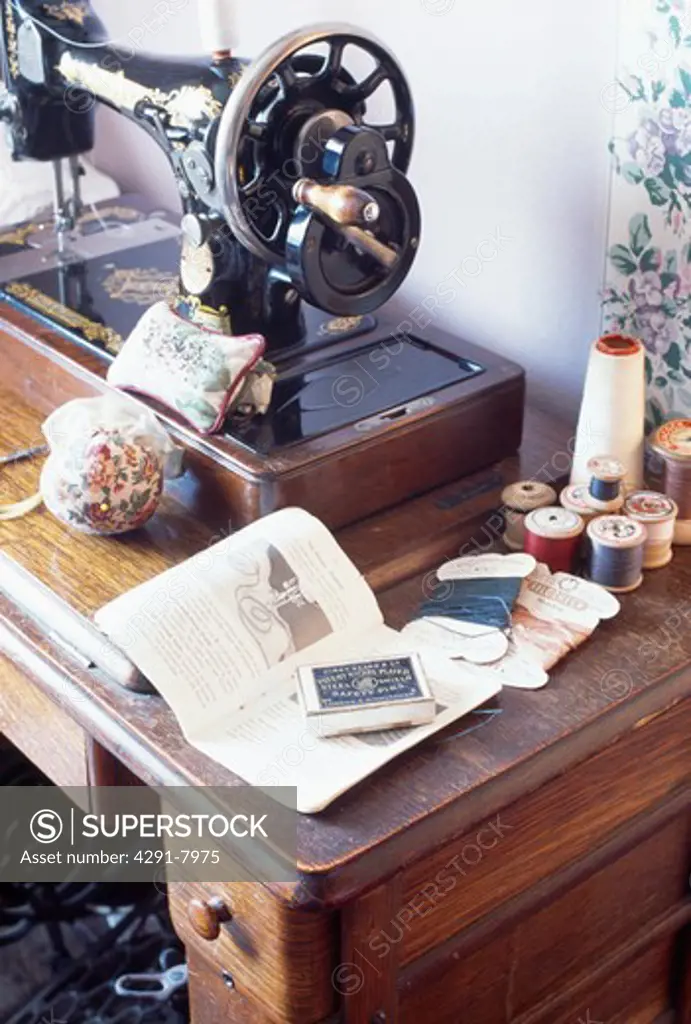 Close-up of vintage Singer sewing-machine with cotton reels on wooden table