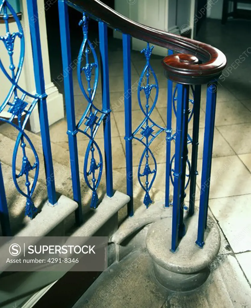 Close-up of blue metal bannisters and mahogany hand-rail on stone staircase