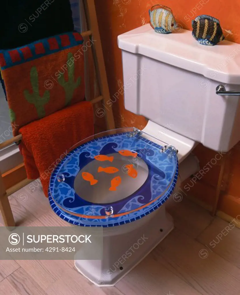 Close-up of novelty seashore-themed perspex toilet seat in red family bathroom