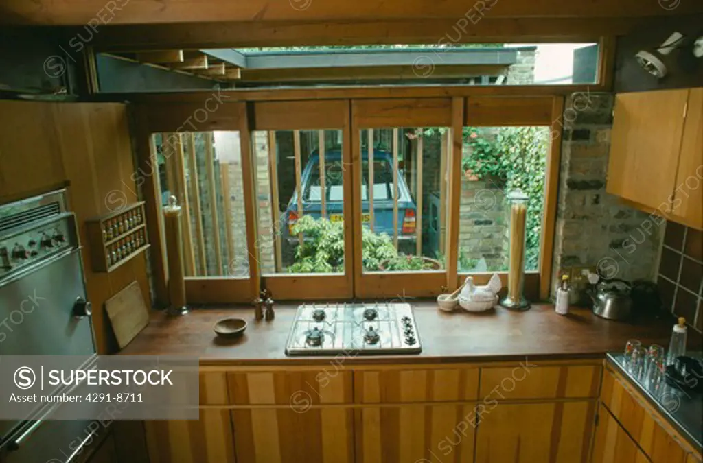 Seventies kitchen with gas hob in wood worktop in front of window with view of small courtyard