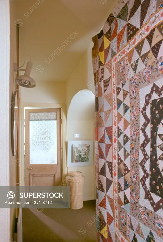 Patchwork quilt on wall of small seventies townhouse hall